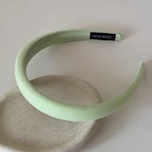 Vue détaillée d'un serre-tête en éponge de tissu vert clair avec étiquette faite main