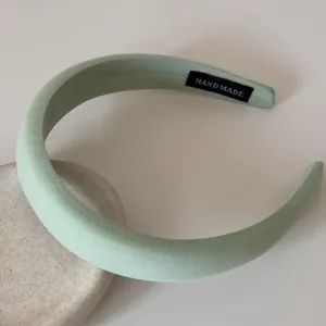 Détail du serre-tête rembourré vert clair montrant la texture et l'étiquette fait main