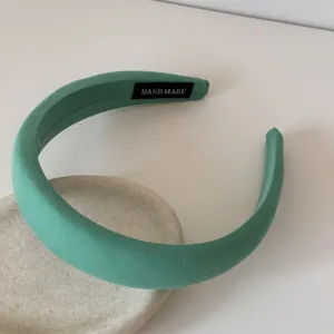 Détail d'un serre-tête en éponge rembourré vert menthe avec une étiquette fait main