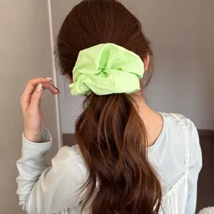 Chouchou en tissu vert vif surdimensionné pour coiffure en queue de cheval sur cheveux bruns