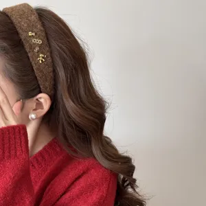 Vue rapprochée d'un serre-tête en peluche marron avec charms dorés sur un modèle