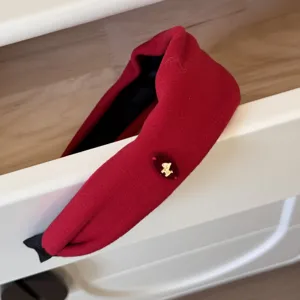 Détail rapproché d'un large serre-tête en velours rouge avec breloque de chien