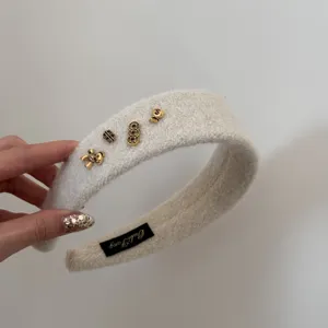 Vue détaillée d'un serre-tête en peluche blanche avec d'élégants charms dorés pour l'hiver