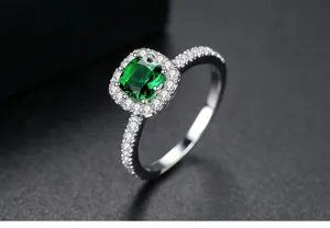 Detalle de anillo de plata con gema verde cuadrada y un halo de piedras brillantes