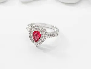 Elegante anillo de gota con piedra roja central y cristales pavé en primer plano