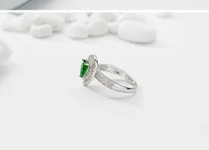 Vista detallada del anillo de cristal verde en forma de pera con engaste halo brillante.