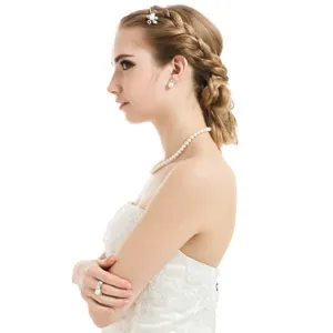 Eleganter Braut-Haarclip mit Perlenblume auf geflochtener Frisur mit weißem Kleid