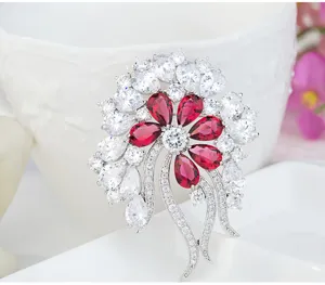 Detailed view of a French vintage flower brooch with red and clear cubic zirconia gemstones