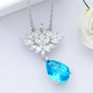 Detailopname van elegante zilveren ketting met blauwe waterdruppel zirkoon en bloemenhanger