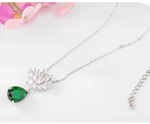 Detailopname van de elegante zilveren bloem- en smaragdgroene druppelhanger-ketting