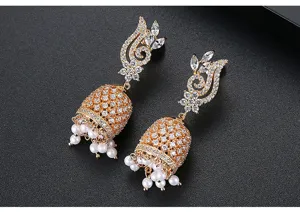 Detailed view of gold-tone bell earrings with sparkling crystals and white pearls.