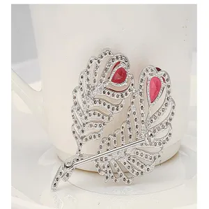 Detailed macro view of a vintage silver feather brooch set with red zircons
