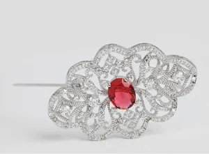 Gros plan sur une broche vintage ajourée avec pierre rouge et oxydes de zirconium