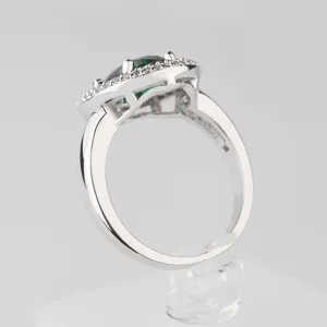 Elegante anillo plateado con un gran circón verde rodeado de pequeñas piedras brillantes
