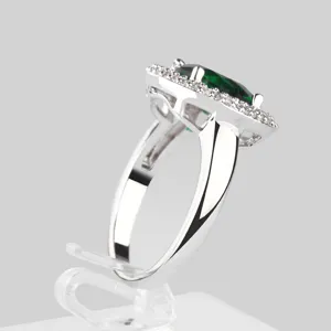 Elegante anillo halo plateado con una gran circonita verde esmeralda de forma ovalada.