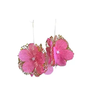 Vista dettagliata di orecchini a fiore in rete rosa con accenti di foglie in metallo oro