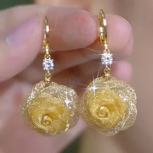 Close-up of gold mesh rose drop earrings with sparkling clear stone
