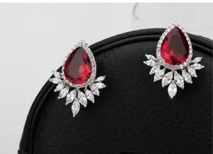 Primer plano de elegantes pendientes con piedra roja y detalles de circonitas marquise