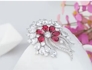 Detailed macro view of a vintage French floral brooch with red and white cubic zirconia