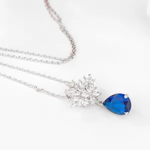 Elegante halsketting met blauwe druppelhanger en fonkelende zirkonia bloemmotieven.