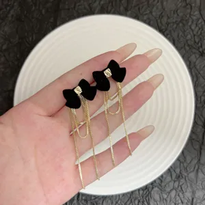 Primo piano di eleganti orecchini a fiocco in velluto nero con lunghe catene dorate