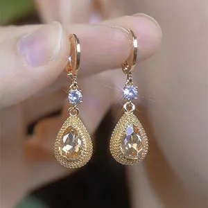 Close-up of vintage champagne teardrop earrings with sparkling crystals in gold.
