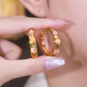 Close-up of retro gold hoop earrings with amber beads and sparkling brown crystals.
