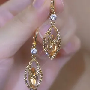 Close-up of elegant gold earrings with champagne marquise stones and sparkling crystals