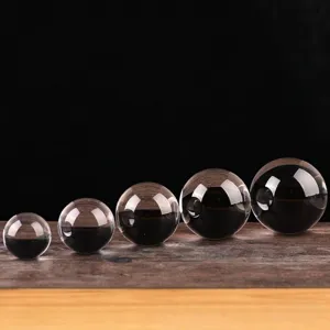 Vijf heldere gepolijste kristallen bollen in verschillende maten op een houten oppervlak