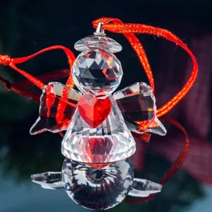 Detailed view of a faceted crystal angel ornament with a red heart and silk ribbon