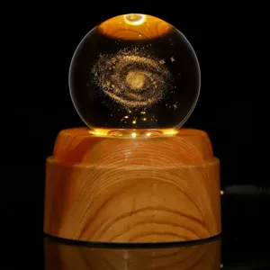 Vista detallada de una bola de cristal de galaxia grabada con láser 3D sobre base de madera.