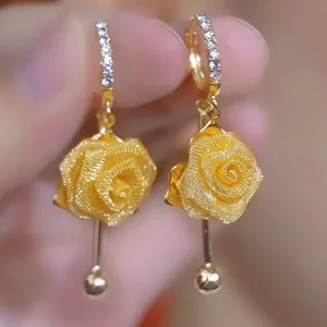 Close-up detail of exquisite gold mesh rose earrings featuring sparkling crystal hoops