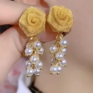 Close-up of golden mesh rose earrings with elegant white pearl tassels detail for women