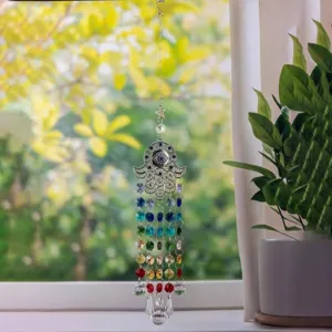 Detailed macro view of the Hamsa Hand and Evil Eye crystal suncatcher by a sunny window