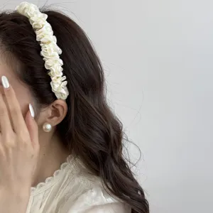 Cream satin pleated headband worn by a woman with elegant wavy hair and pearl earring