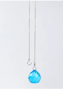 Detalle de una bola de cristal azul facetada con cadena plateada para colgar