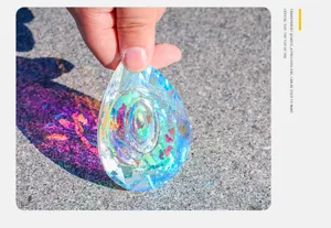 Mano che tiene un ciondolo in cristallo AB sfaccettato che riflette la luce colorata