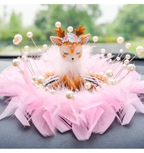 Detailed close-up of a cute deer car dashboard ornament with pink feathers and pearls