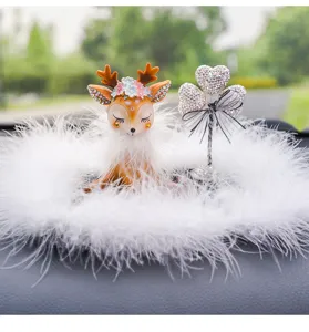 Detailed view of a cute deer car ornament surrounded by soft white feathers