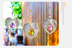 Decorative angel wing sun catchers with vibrant crystal pendants hanging in bright sunlight.
