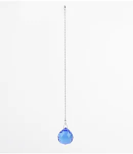 Dettaglio del ciondolo a sfera in cristallo blu sfaccettato su una catena d'argento.