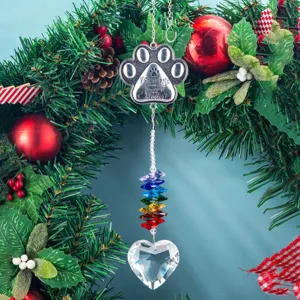 Close-up detail of a crystal suncatcher with metal paw print and rainbow beads hanging on wreath.