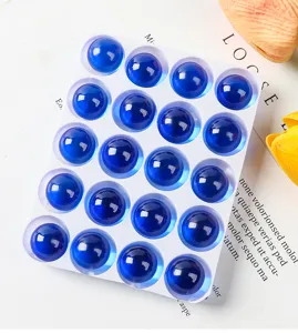 Makroaufnahme von zwanzig durchscheinenden blauen Glasmurmeln in einer weißen Schale.