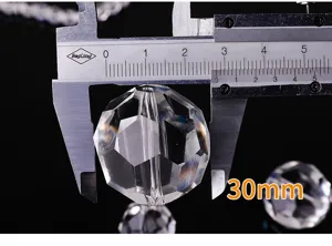 Macro detail showing a 30mm faceted clear crystal ball bead measured with a caliper.