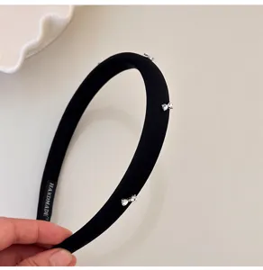 Primer plano de una elegante diadema acolchada negra con lazos de pedrería fina.