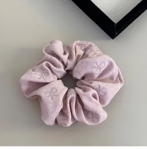 Primo piano dettagliato dei motivi a fiocco rosa ricamati su un elastico per capelli in tessuto