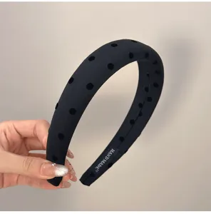 Gros plan d'un serre-tête noir rembourré avec pois en velours et étiquette fait main