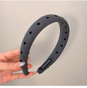 Gros plan d'un serre-tête gris rembourré avec motifs de cœurs noirs et étiquette