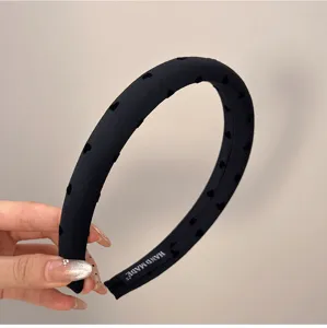 Gros plan d'un serre-tête en tissu noir avec cœurs en velours et étiquette faite main.