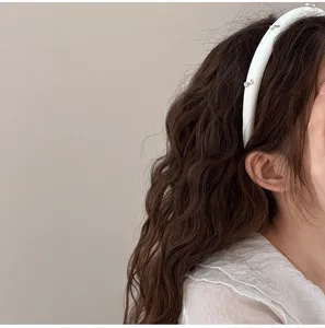 Primer plano de una diadema blanca acolchada con pequeños lazos plateados en el pelo